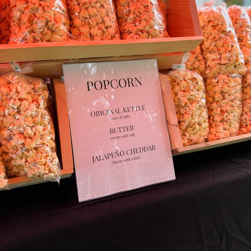 An event table stacked with bags of Original Kettle, Butter, and Jalapeño Cheddar popcorn