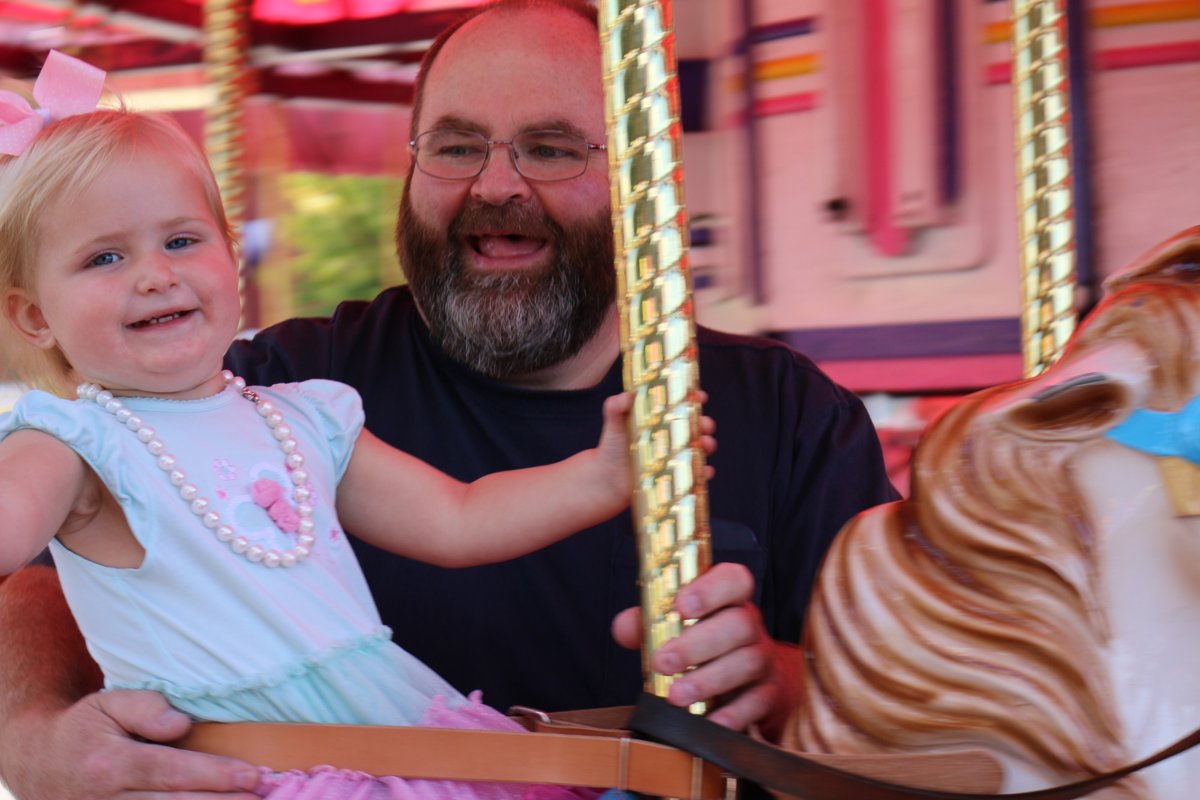 Greg laughing on a carousel with his granddaughter